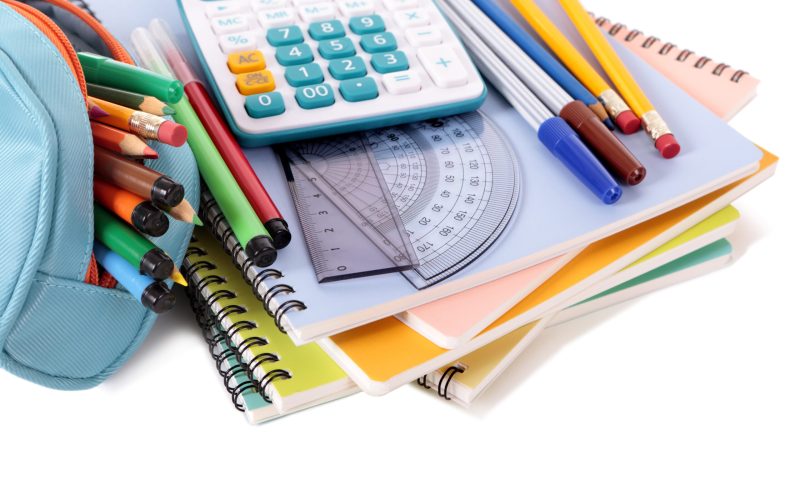 Various school supplies including notebooks, calculator and pencil case isolated against a white background